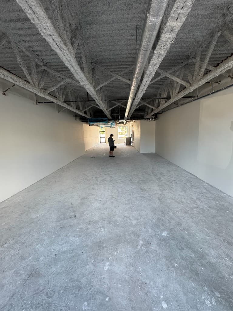 Commercial interior under construction with exposed ceiling structure and concrete floors