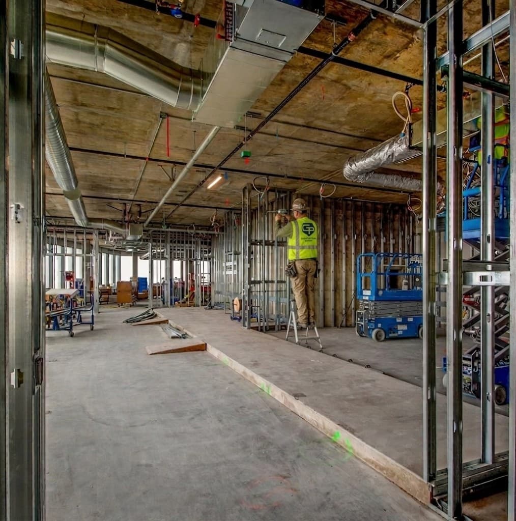 GP Contracting Group worker framing a commercial interior build-out with metal stud walls and exposed ceiling infrastructure