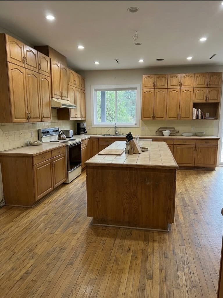 Kitchen before renovation with oak cabinets and tile countertops