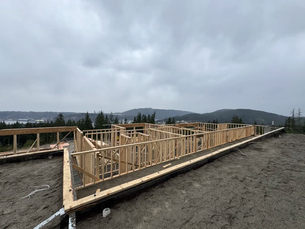 Residential framing on a hilltop lot with forest and water views