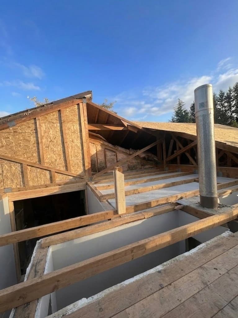 Roof trusses and OSB sheathing on a residential home under construction against a clear blue sky